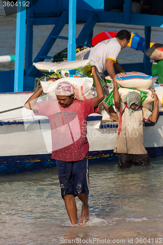 Image of Men transports cargo from ship