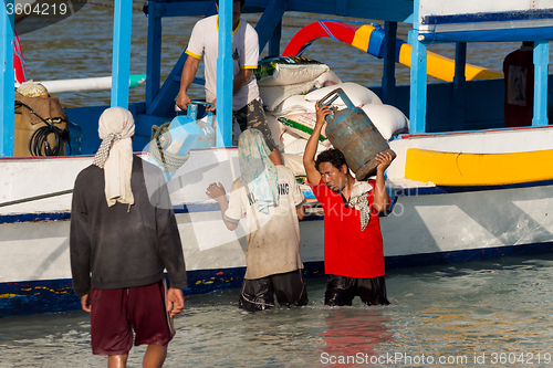 Image of Men transports cargo from ship