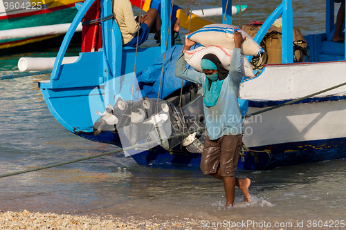 Image of Men transports cargo from ship