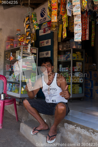 Image of Indonesian man in front of his store in Manado shantytown