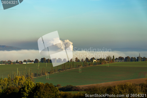 Image of smoking chimneys in from factory hidden in mist