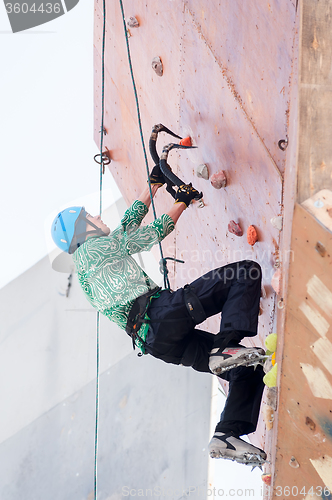 Image of Man climbs upward on ice climbing competition