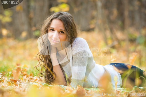Image of Young beautiful girl lies on the Scourge in the yellow fallen leaves