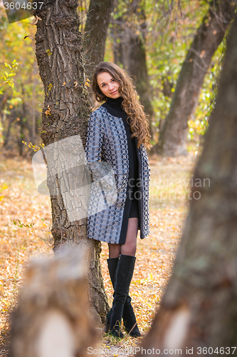 Image of A young beautiful girl leaned back against the tree in the forest