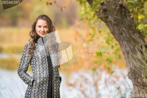 Image of Portrait of a young girl near the tree on a background of autumn river