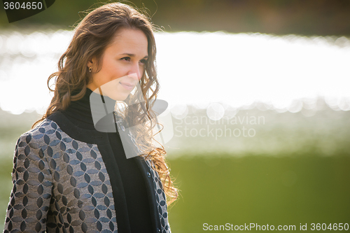 Image of Portrait of a young girl on a background of the river in the cool autumn weather