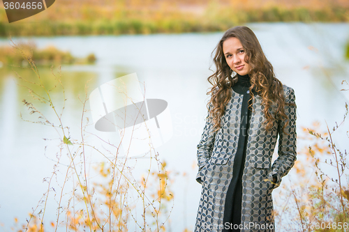 Image of Portrait of a young girl on the background of a lake in autumn weather