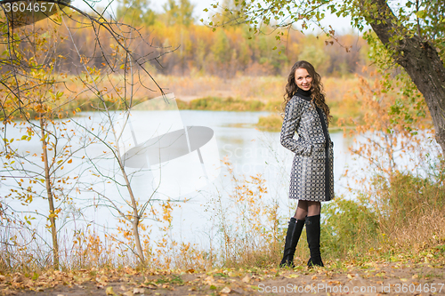 Image of A young girl walks by the river in the autumn forest
