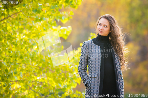 Image of Cute young girl looking to the left on the background of autumn yellow foliage