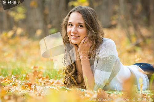 Image of Young beautiful girl lies on the weave at a picnic in the autumn forest