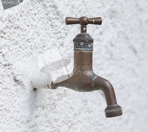 Image of Old water tap on a white wall 