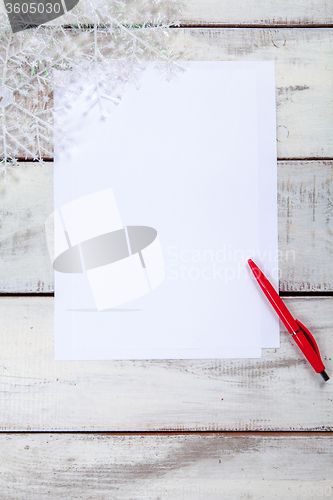 Image of The blank sheet of paper on the wooden table with a pen 