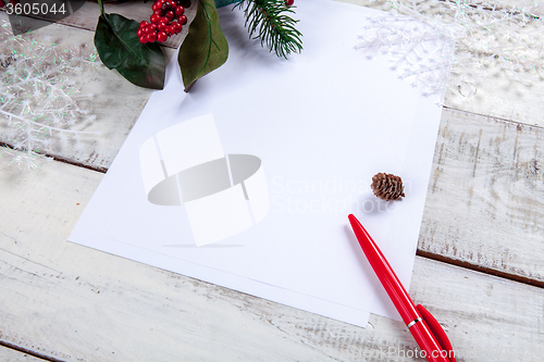 Image of The blank sheet of paper on the wooden table with a pen 