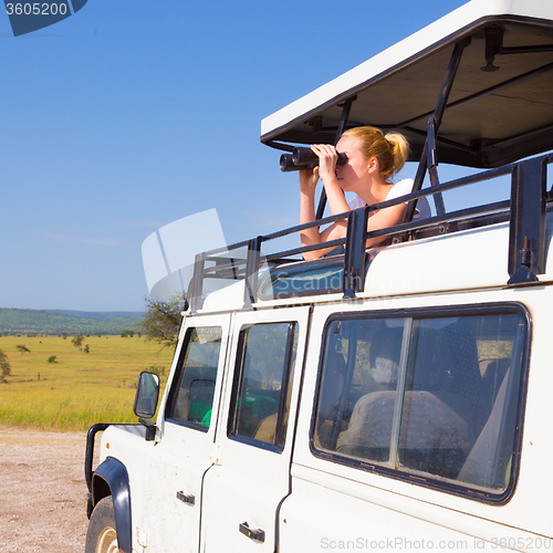 Image of Woman on safari looking through binoculars.