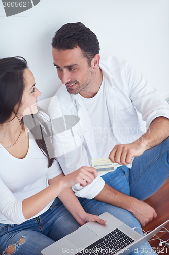 Image of relaxed young couple working on laptop computer at home