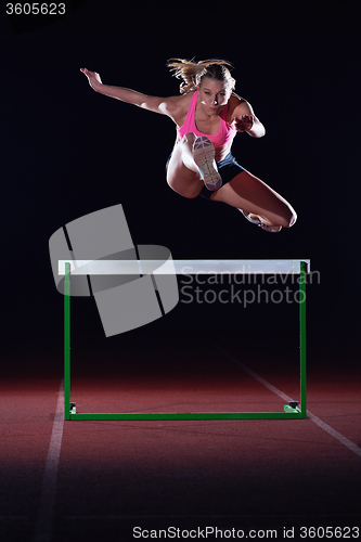 Image of woman athlete jumping over a hurdles