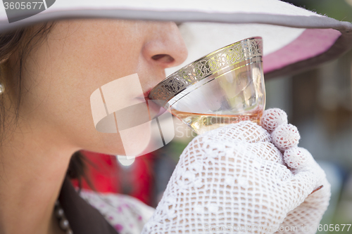 Image of 1920s Dressed Girl with Hat, Gloves and Glass of Wine