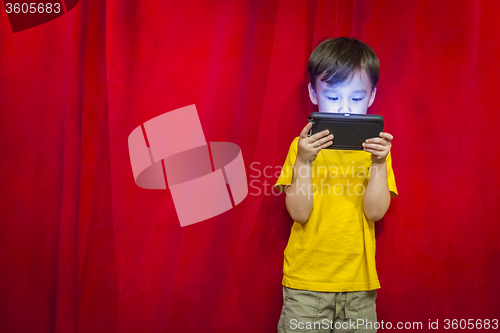 Image of Mixed Race Boy Watching Cell Phone in Front of Curtain