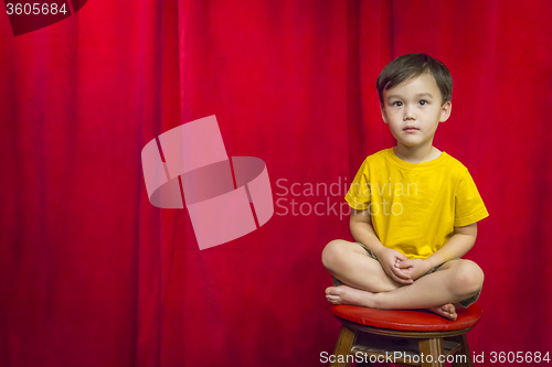 Image of Mixed Race Boy Sitting on Stool in Front of Curtain