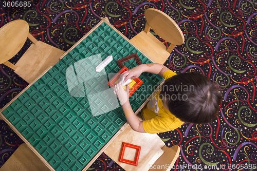 Image of Overhead of Boy Playing With His Toys at Table