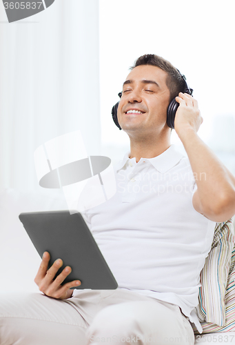 Image of smiling man with tablet pc and headphones at home
