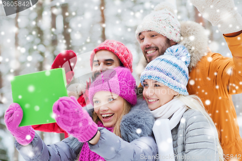 Image of smiling friends with tablet pc in winter forest