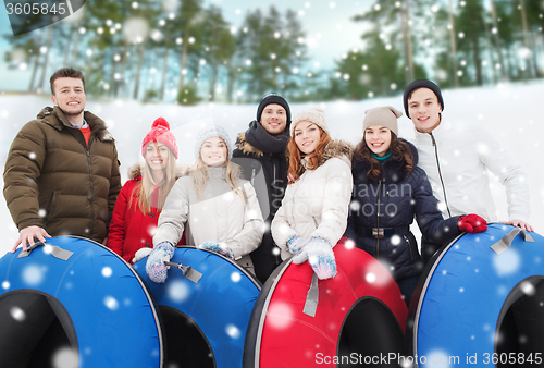 Image of group of smiling friends with snow tubes