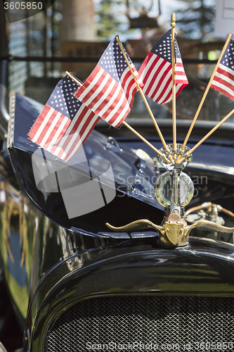 Image of American Flags On Hood Ornament of Classic Car