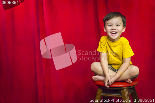 Image of Laughing Boy Sitting on Stool in Front of Curtain