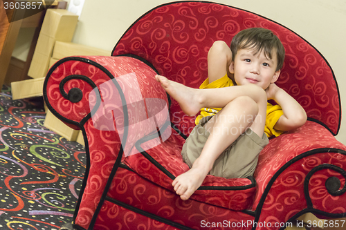Image of Mixed Race Boy Relaxing in Comfortable Red Arm-Chair