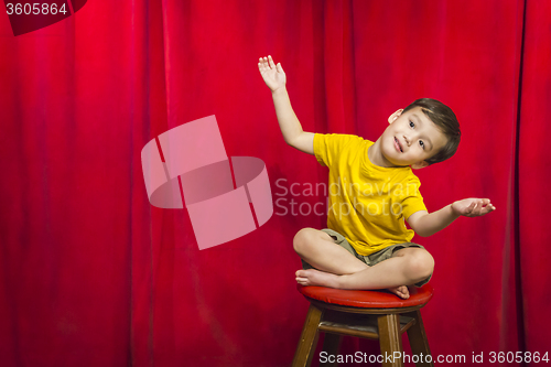 Image of Mixed Race Boy Sitting on Stool in Front of Curtain