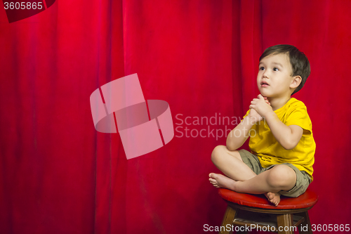Image of Mixed Race Boy Sitting on Stool in Front of Curtain
