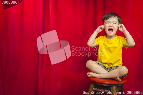 Image of Boy, Fingers In Ears on Stool in Front of Curtain