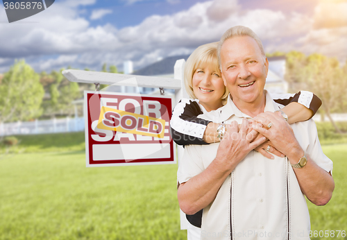 Image of Senior Couple in Front of Sold Real Estate Sign and House