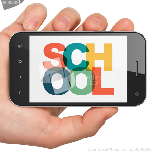 Image of Education concept: Hand Holding Smartphone with School on  display