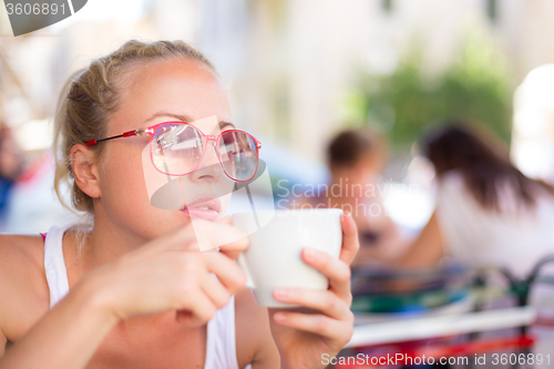 Image of Woman drinking coffee outdoor on street.