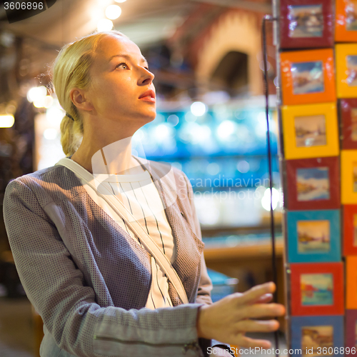 Image of Casual blond woman shopping for vacation souvenirs.