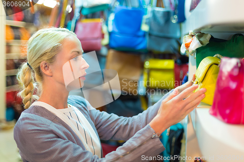 Image of Casual blond woman shopping for leather bag.