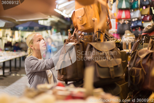 Image of Casual blond woman shopping for leather bag.