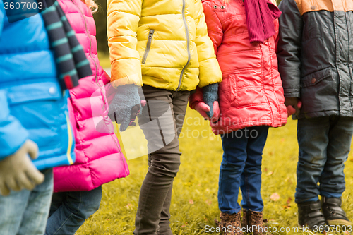 Image of close up of children holding hands in autumn park