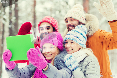 Image of smiling friends with tablet pc in winter forest