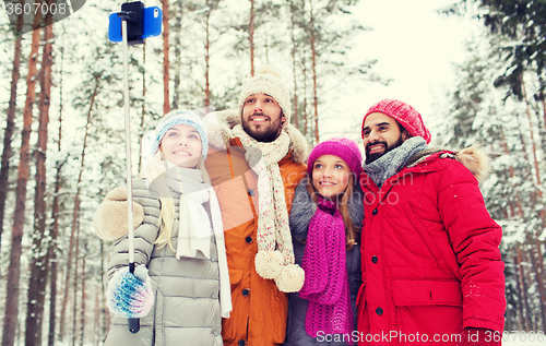 Image of smiling friends with smartphone in winter forest