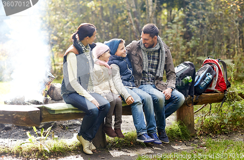 Image of happy family sitting on bench and talking at camp
