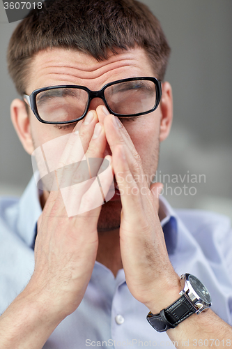 Image of tired businessman with eyeglasses at office 