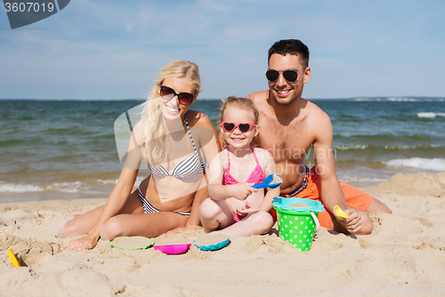 Image of happy family playing with sand toys on beach