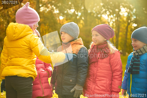 Image of kids in autumn park counting and choosing leader