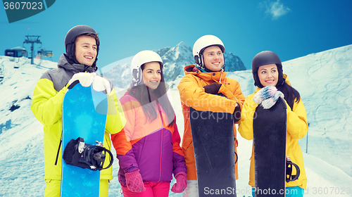 Image of happy friends with snowboards over mountains