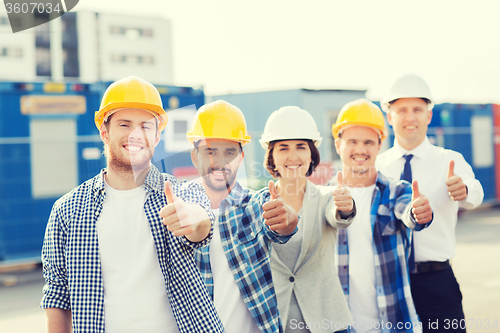 Image of group of smiling builders in hardhats outdoors