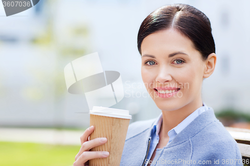 Image of smiling woman drinking coffee outdoors