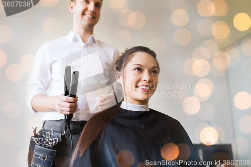 Image of happy woman with stylist making hairdo at salon